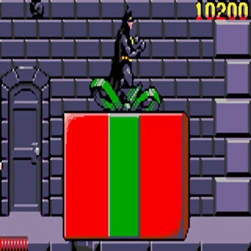 Batman damunt d’una gran capsa vermella amb cinta verda, davant d’una façana de maons.