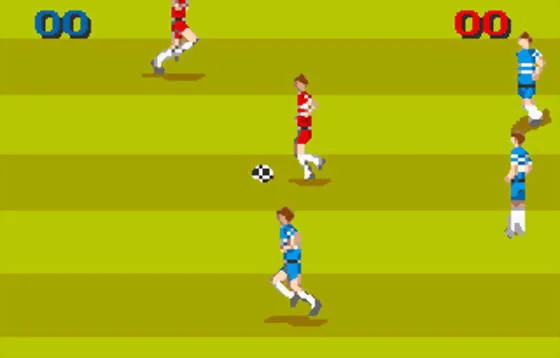 Un futbolista de vermell avança amb la pilota mentre diversos rivals de blau ocupen el camp visible.