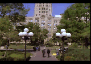 Parc universitari amb persones i un edifici alt al fons.