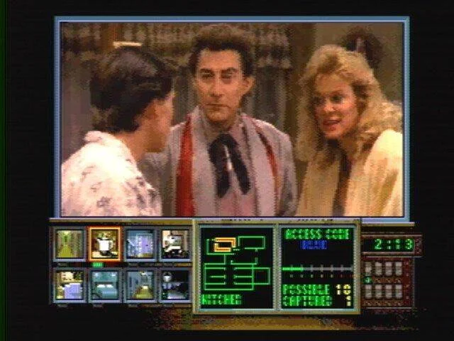 Interfície de Night Trap amb una escena familiar a la finestra de vídeo i les icones de les habitacions a sota.