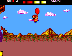 Alex Kidd vola subjectat a un globus vermell sobre un paisatge muntanyós.