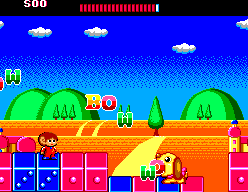 Alex Kidd avança per blocs de colors davant d’un enemic groc al Toy World.