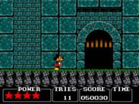 Mickey avança davant d’una porta arquejada en un passadís de pedra mentre el marcador mostra energia, intents, puntuació i temps.