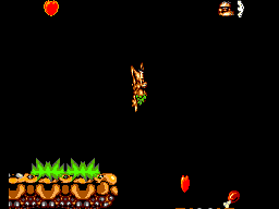 Chuck saltant entre plataformes rocoses, fruites i un enemic vermell en la versió de Master System.