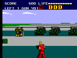 Duke en primer pla apunta contra soldats situats entre vehicles militars en una escena de Sega Master System.