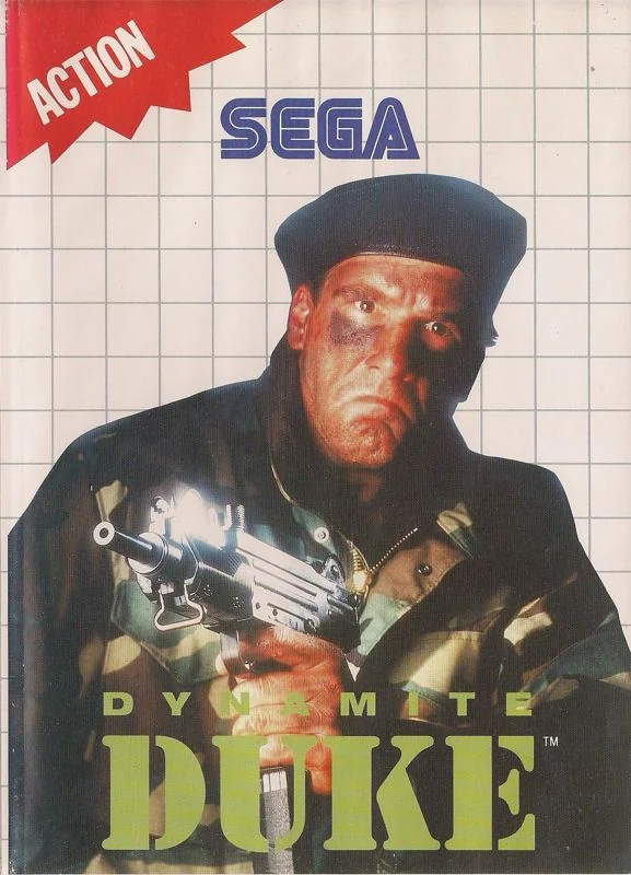 Portada europea de Dynamite Duke per a Sega Master System, amb Duke armat sobre un fons quadriculat.