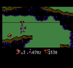 Earthworm Jim suspès d’un cable sobre un buit entre plataformes rocoses.