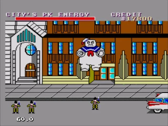 El Marshmallow Man gegant davant d’uns edificis, amb tres caçafantasmes i el vehicle a la dreta.