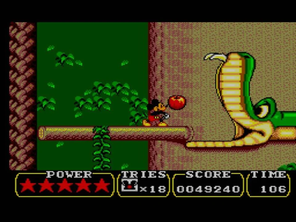 Mickey sosté una poma davant d’una cobra en una etapa de Land of Illusion.