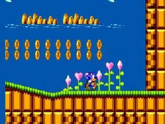 Sonic recull anells en un escenari costaner ple de flors, blocs i plataformes.