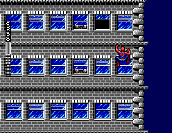 Spider-Man avança arrapat a una façana grisa amb finestres blaves.