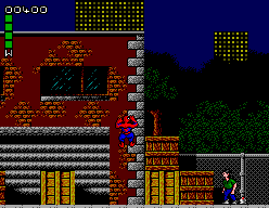 Spider-Man aferrat a una paret en un carrer nocturn, amb un enemic a la vorera.